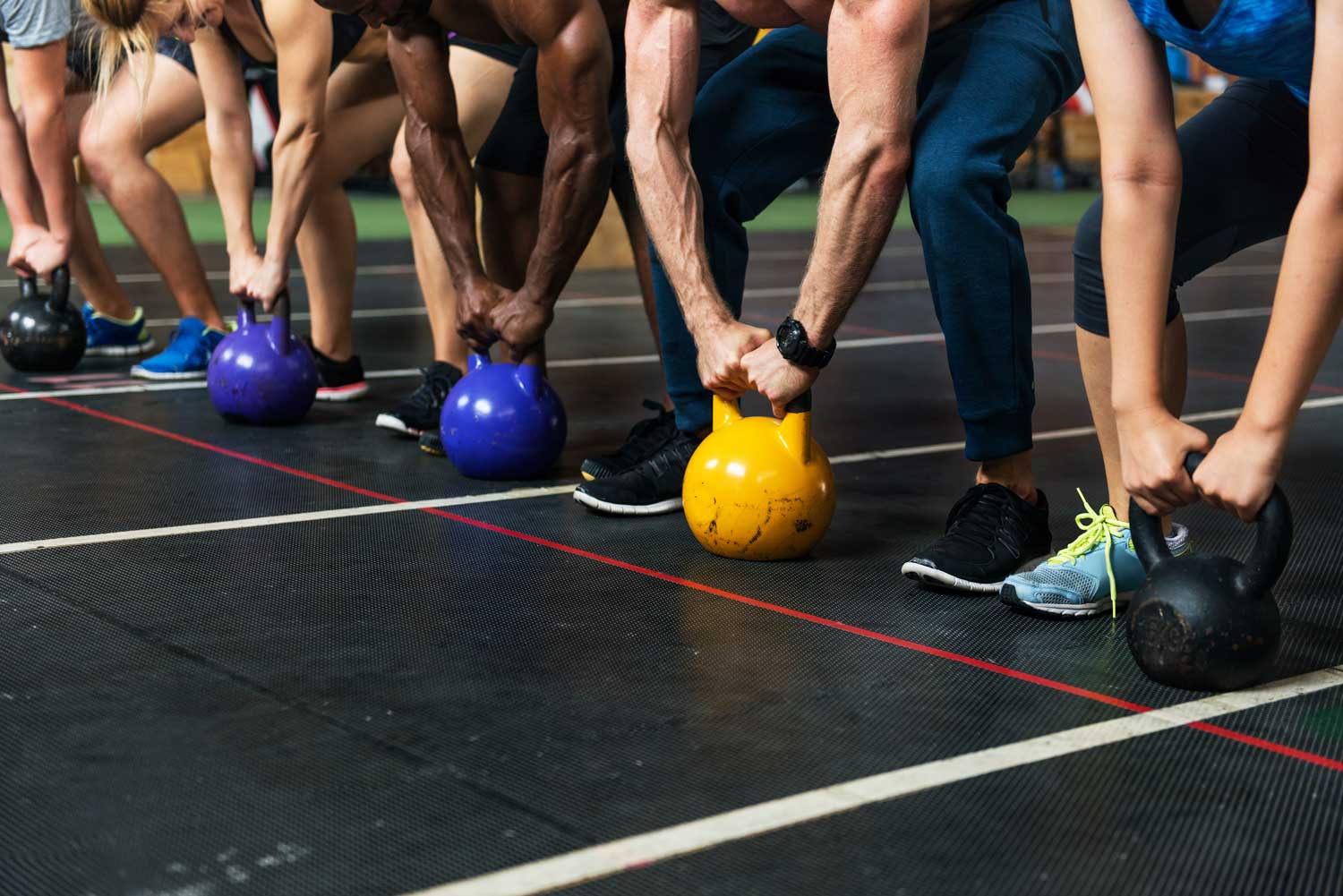 Gruppe von Athleten mit Kettlebells im Gym