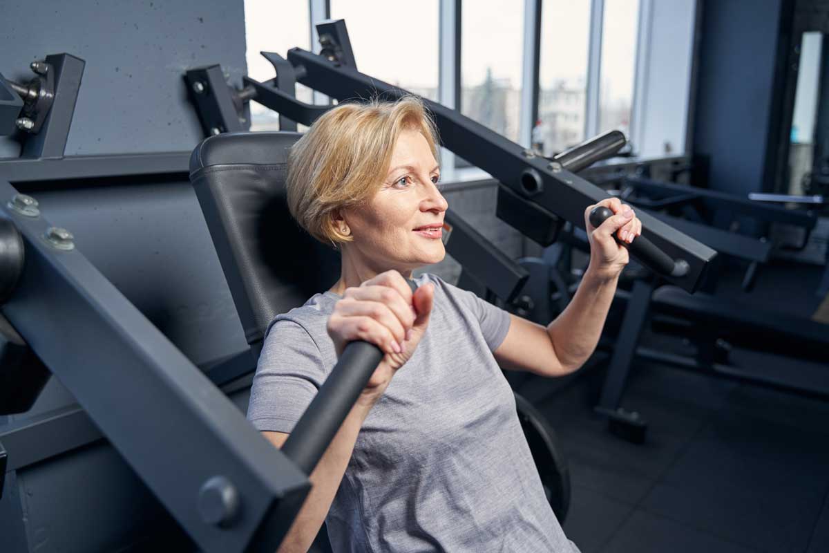 Frau-mittleren-Alters-trainiert-an-Fitnessgerät